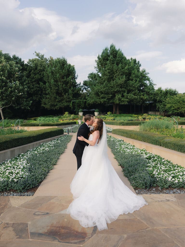 Newlyweds kissing in garden walkway at Dallas Arboretum